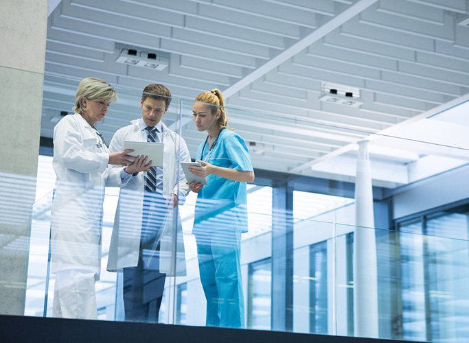 Medical team discussing over digital tablet in corridor